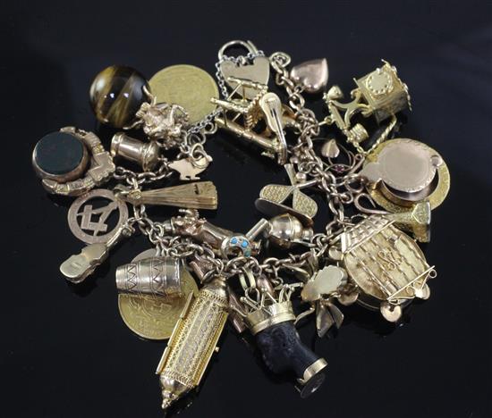 An early 20th century 18ct gold charm bracelet, hung with twenty seven assorted mainly 9ct gold charms,